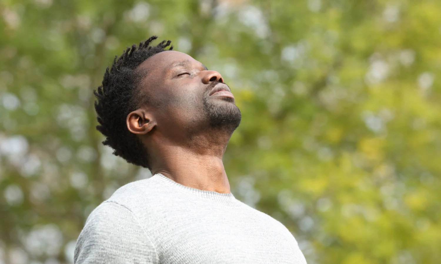 man closing eyes in nature
